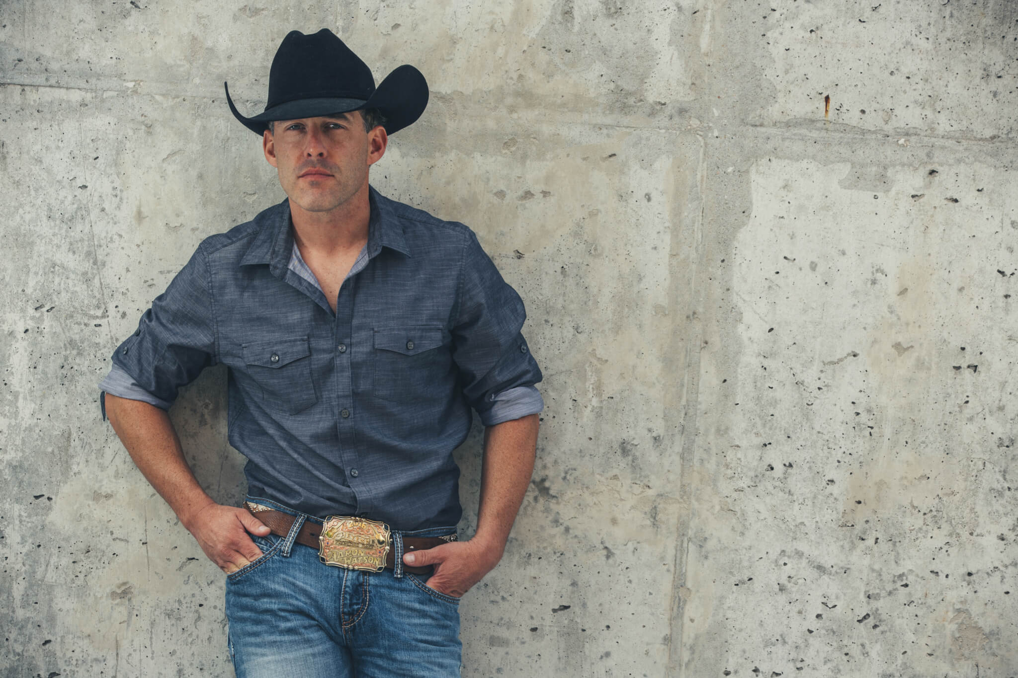 Aaron Watson standing in front of a gray wall